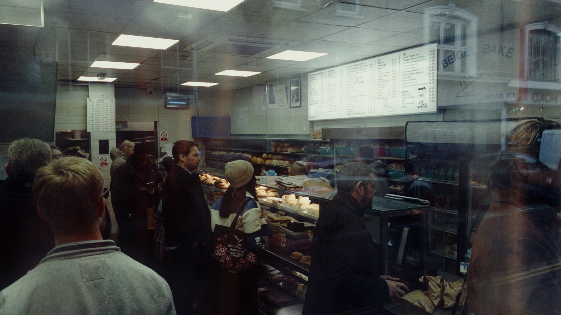 Beigel Bake on Brick Lane at night, seen through the window with the street reflected in the glass; S444 Film Lab: Vision3 250D negative, 2383 print