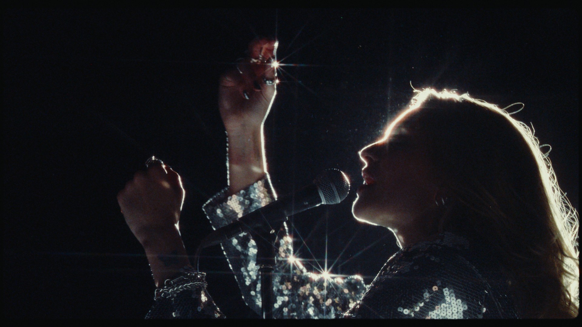 A backlit singer at a microphone, shot on a Sony F35 and put through S444 Film Lab: Vision3 250D negative, 2383 print